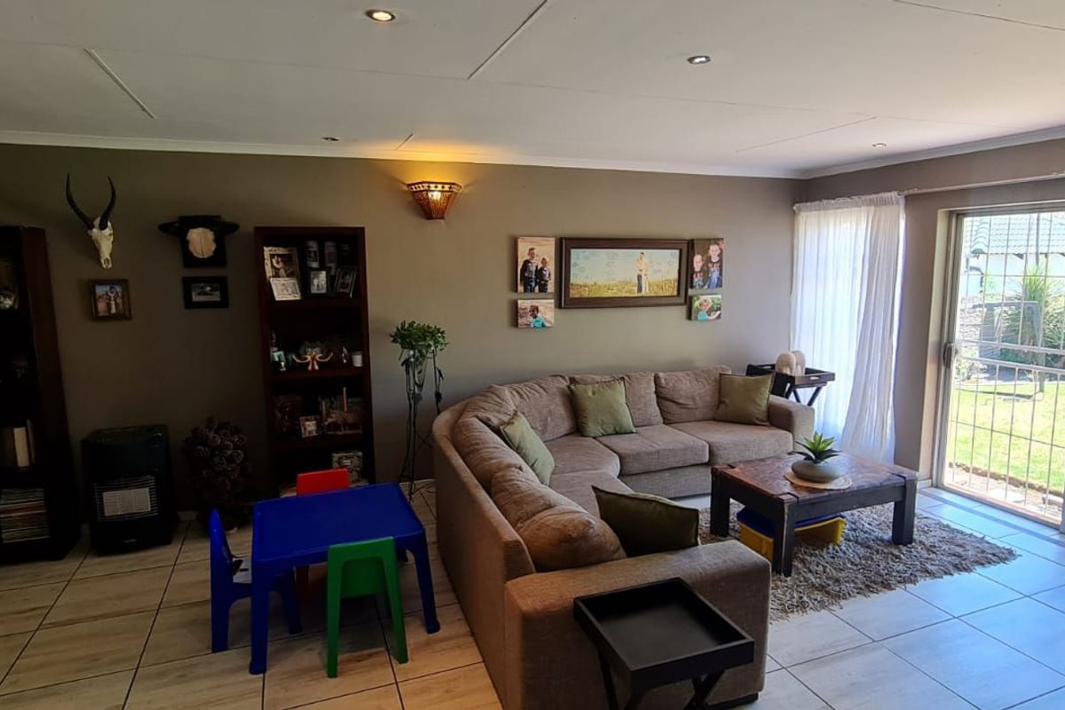 Spacious living room featuring tiled flooring, recessed ceiling lighting, and large sliding glass doors providing direct access to the rear garden.