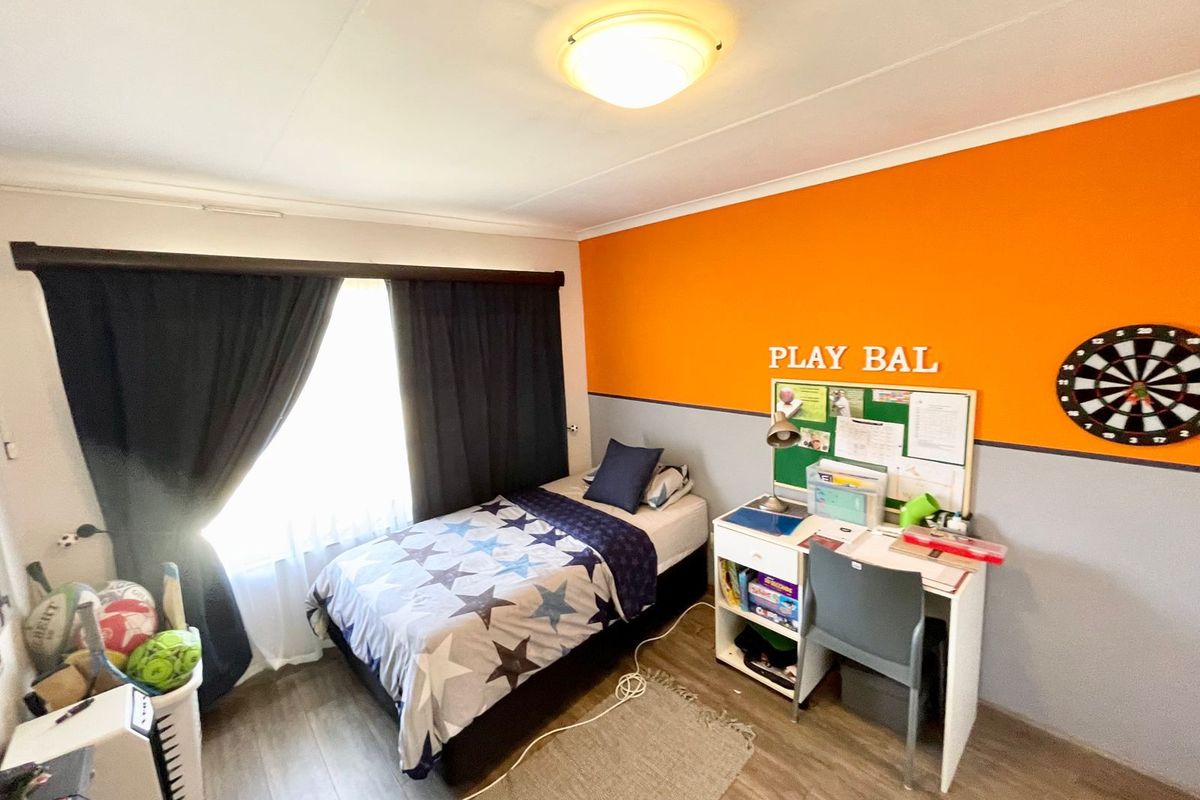 A bedroom featuring wood-look flooring, a large window with curtain tracks, and a ceiling-mounted light fixture.