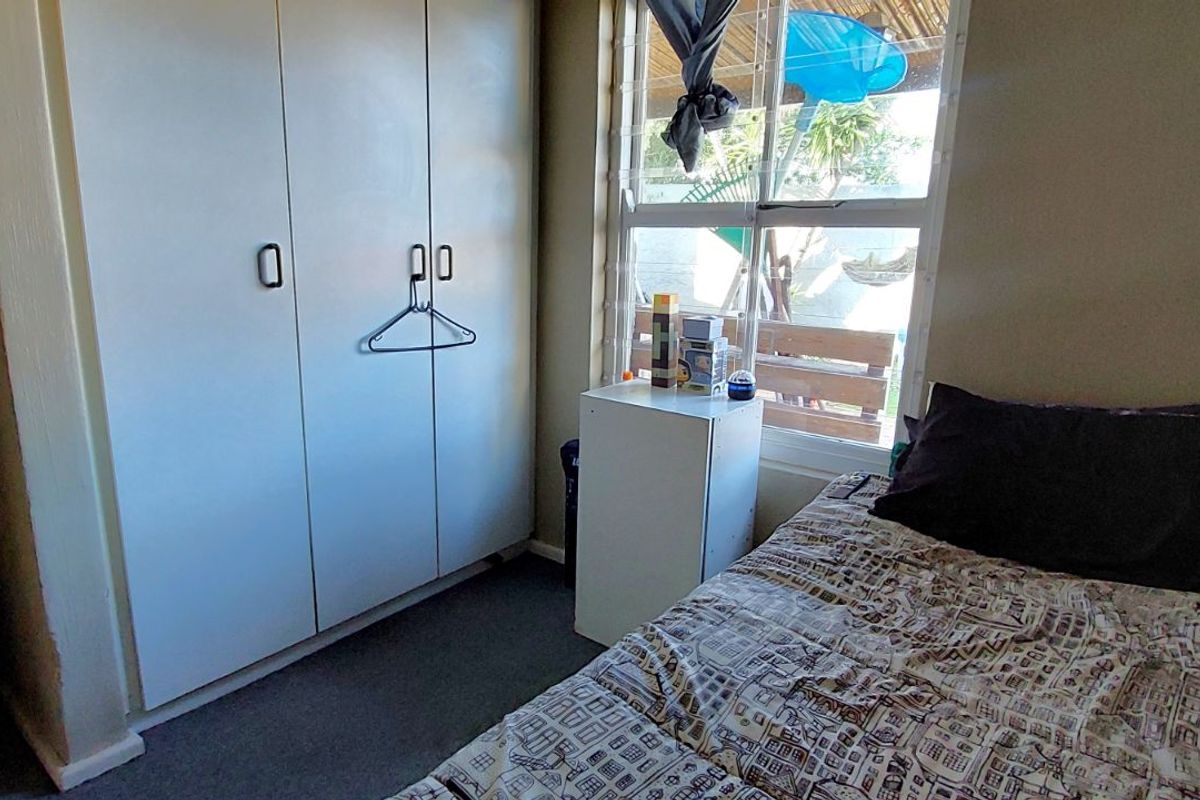 A functional bedroom featuring built-in cupboards and a window providing natural light.