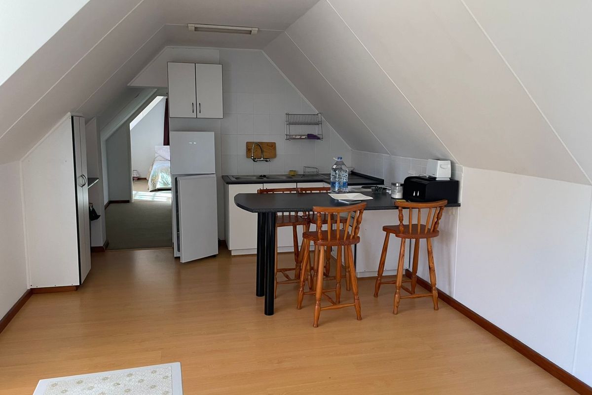 Compact attic kitchen featuring built-in cabinetry, a breakfast bar, and sloped ceilings, providing a functional kitchenette space within the upper level.