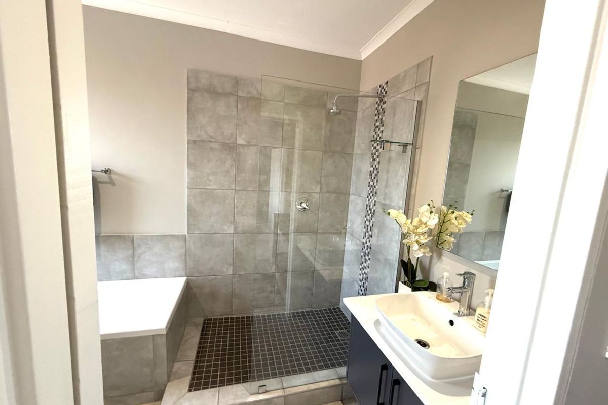 Modern bathroom featuring a walk-in shower with glass screen, built-in bathtub, and a contemporary vanity with a vessel sink.