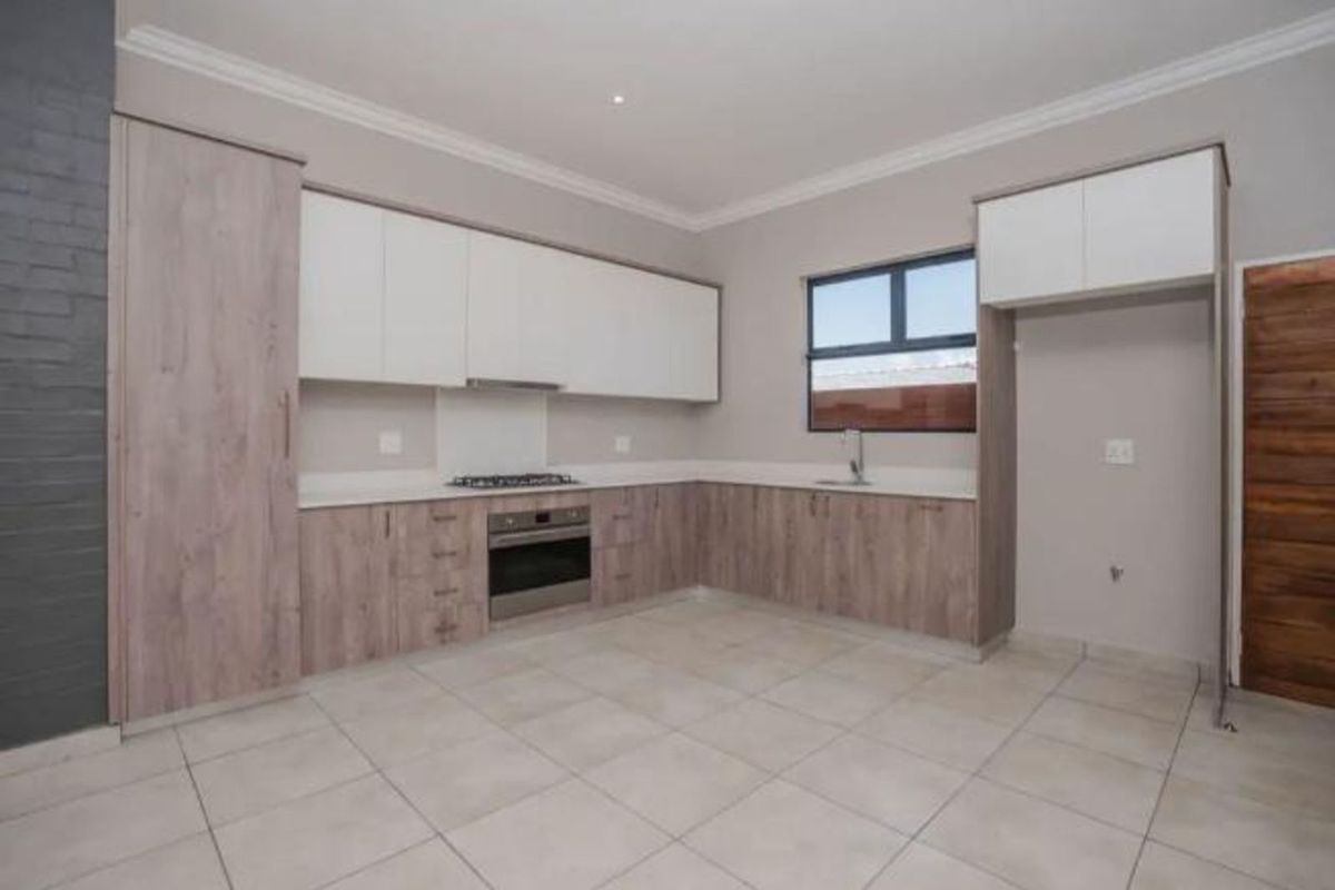 Modern kitchen featuring two-tone cabinetry, built-in oven, gas hob, extractor fan, and tiled flooring with a neutral color palette.