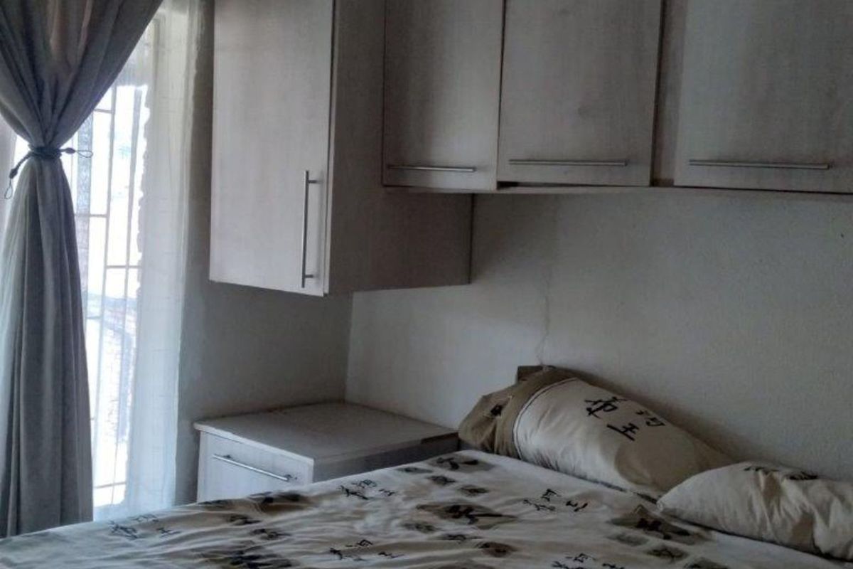 A bedroom featuring built-in overhead cabinetry and a side storage unit, providing functional storage space.