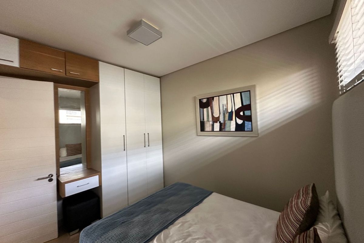 A well-maintained bedroom featuring built-in white cabinetry, integrated vanity with mirror, and modern overhead lighting.