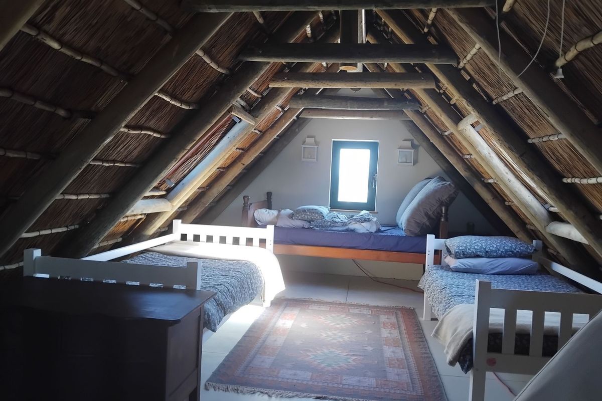 Attic bedroom featuring a vaulted thatched roof with exposed timber rafters and tiled flooring.