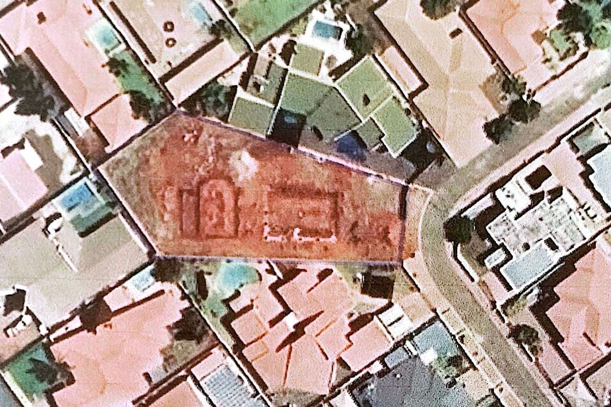 Aerial view of a vacant residential plot situated within an established suburban neighborhood, showing clear boundaries and surrounding properties.
