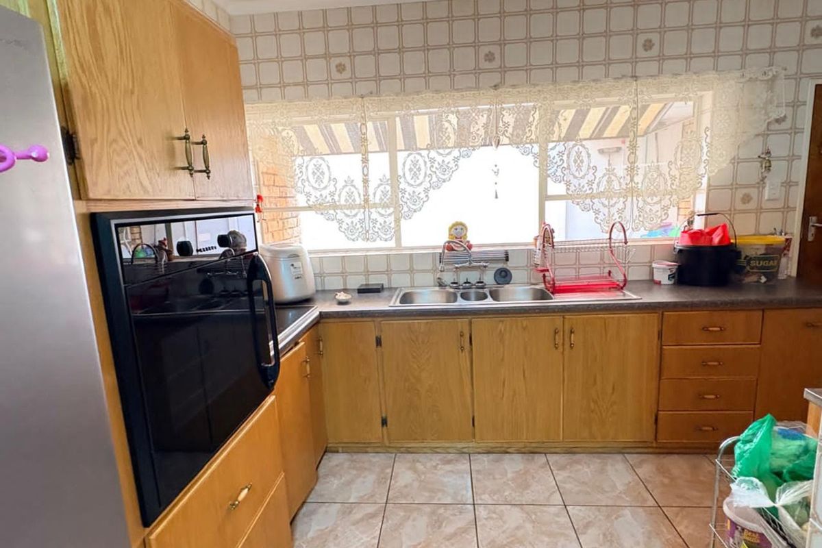 A functional kitchen featuring wood-finish cabinetry, a double-basin sink, and a built-in oven, offering a traditional layout with ample counter space.