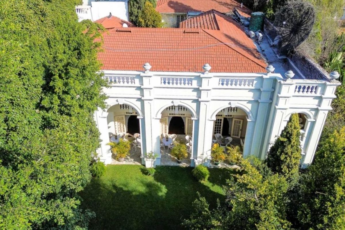 Aerial view of a classic residence featuring a terracotta tiled roof, arched patio columns, and a well-maintained garden.