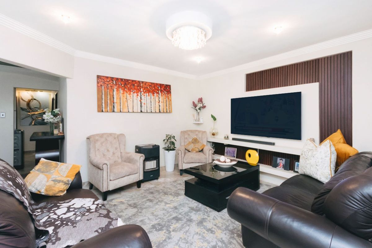 A well-maintained living room featuring a built-in media wall with decorative timber slat paneling and recessed shelving.