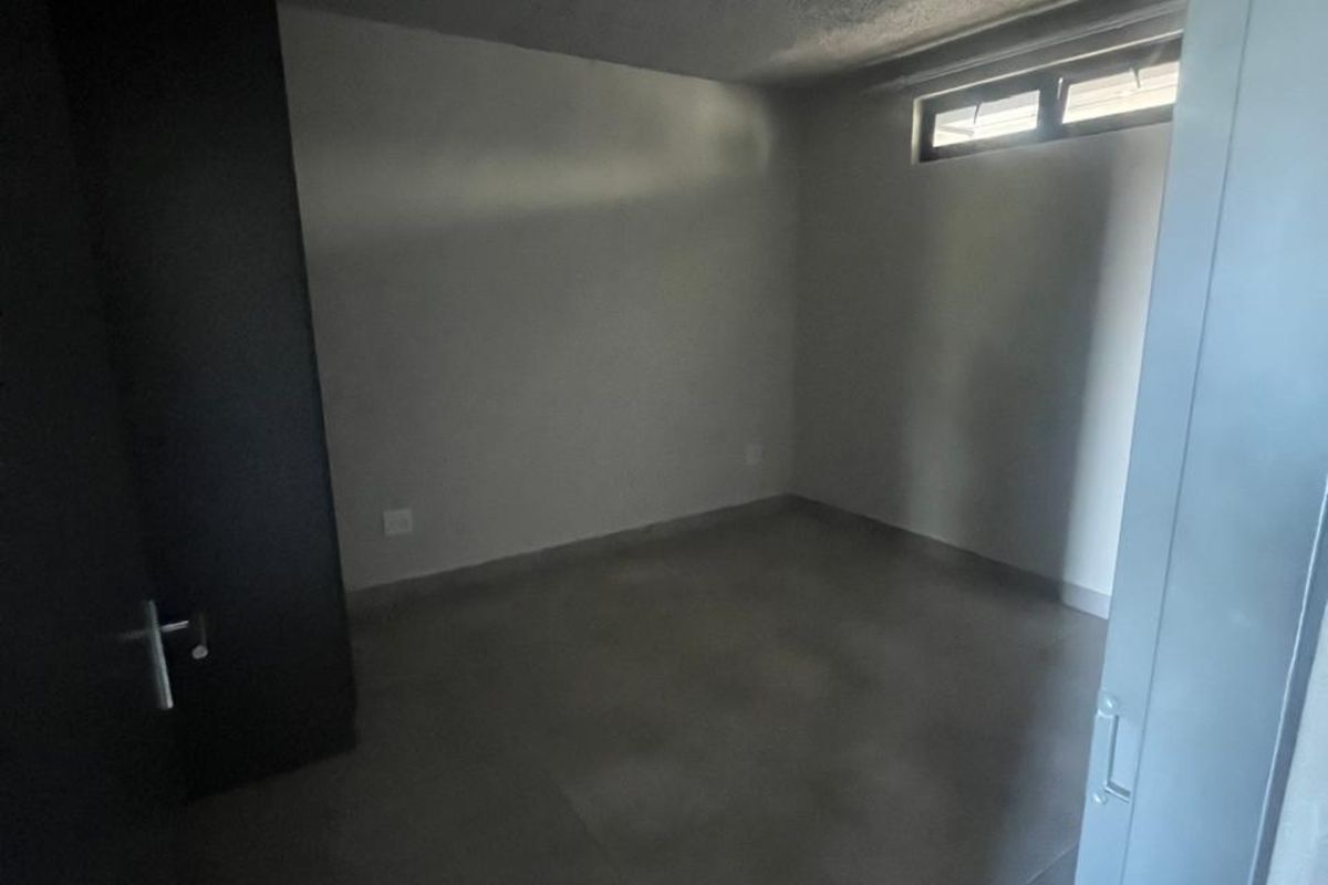 An empty bedroom featuring tiled flooring, a built-in cupboard, and a high-set horizontal window providing natural light.