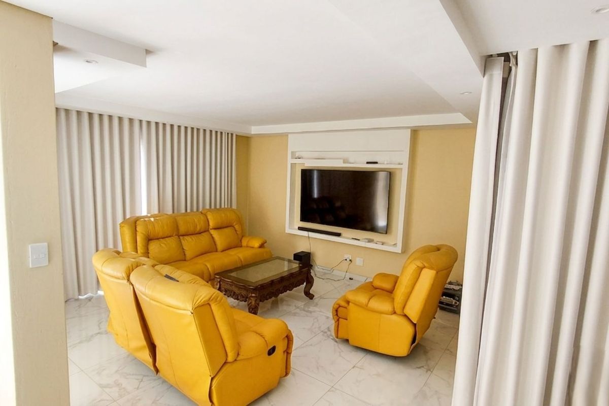 A bright living room featuring marble-look floor tiles, recessed ceiling lighting, and a built-in media wall unit.