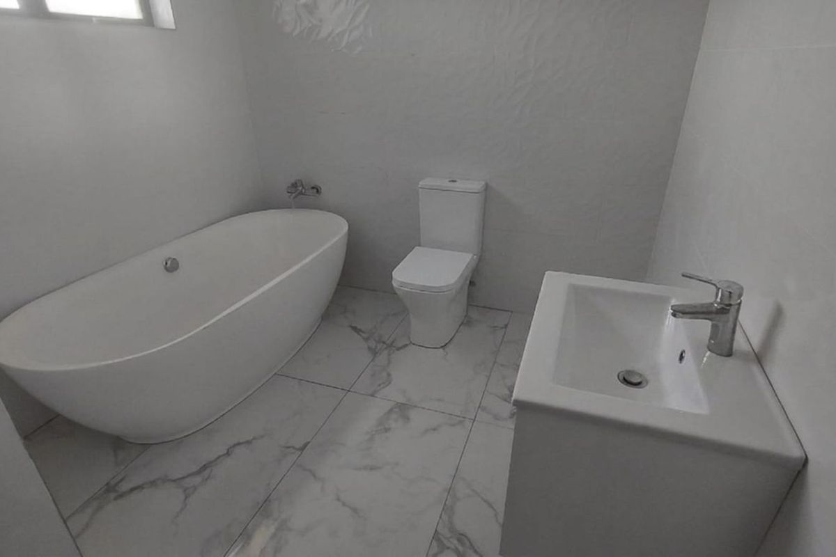 Modern bathroom featuring a freestanding bathtub, a contemporary toilet, and a sleek vanity basin with marble-look floor tiling.