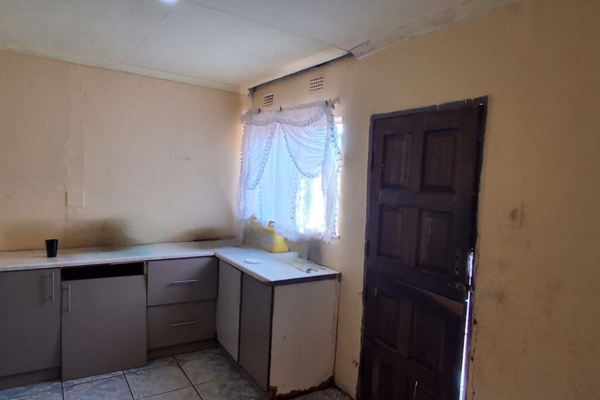 A dated kitchen area featuring built-in cabinetry, tiled flooring, and direct access to an exterior door.