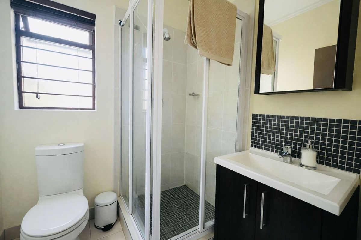 A functional bathroom featuring a glass-enclosed shower, a modern vanity with a basin, and a standard toilet.