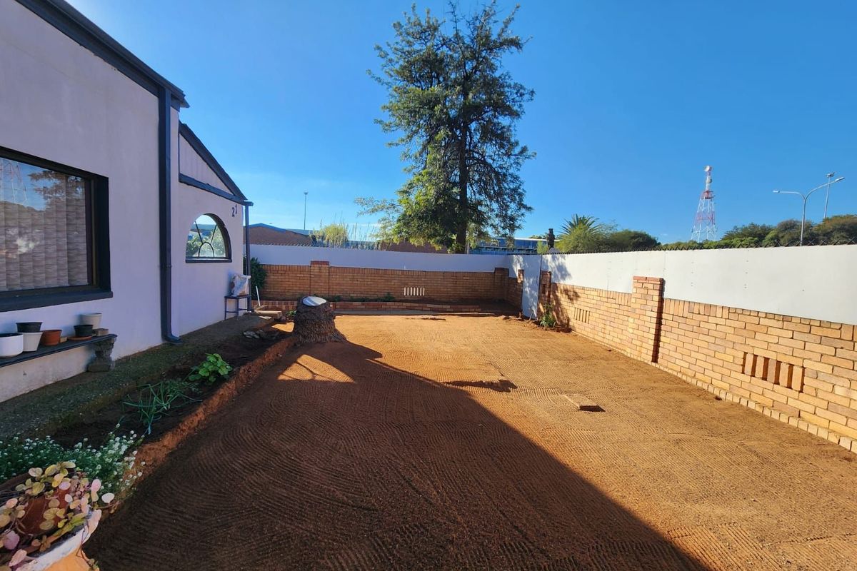 A spacious rear garden area featuring a brick boundary wall and a large, cleared soil surface ready for landscaping.