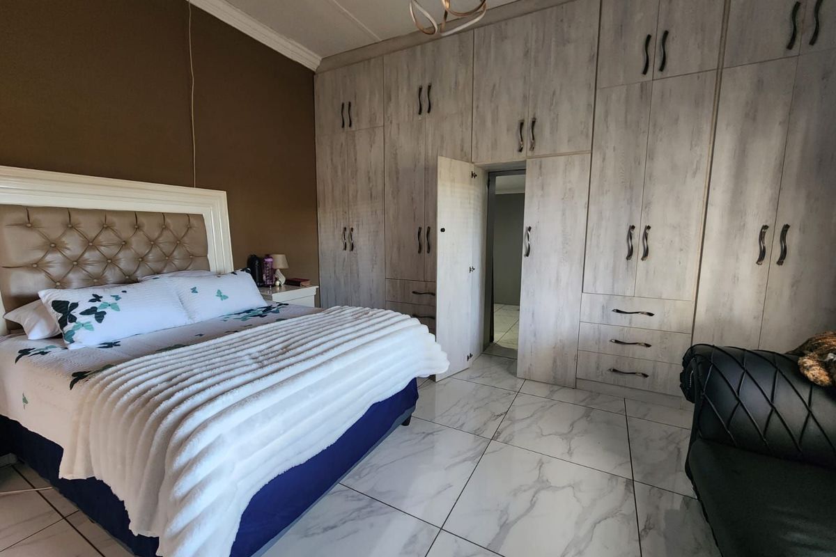Spacious bedroom featuring extensive built-in cabinetry with integrated storage and modern marble-look floor tiling.