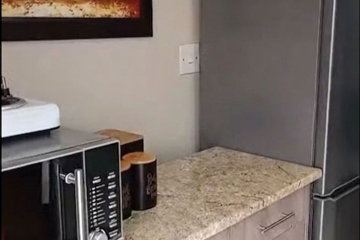 A compact kitchen area featuring granite countertops, light wood-grain cabinetry, and space for a refrigerator.