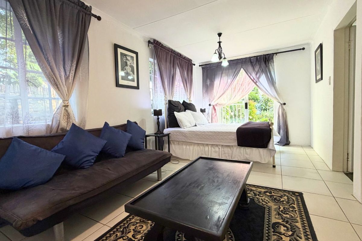 A bedroom featuring tiled flooring, large windows, and a sliding glass door providing access to the exterior.