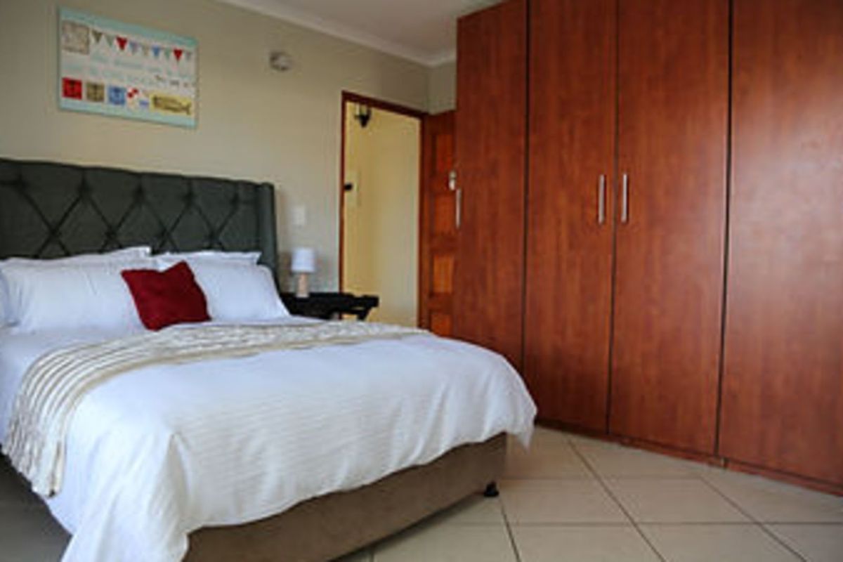A bedroom featuring built-in wooden cupboards and tiled flooring, providing ample storage space.