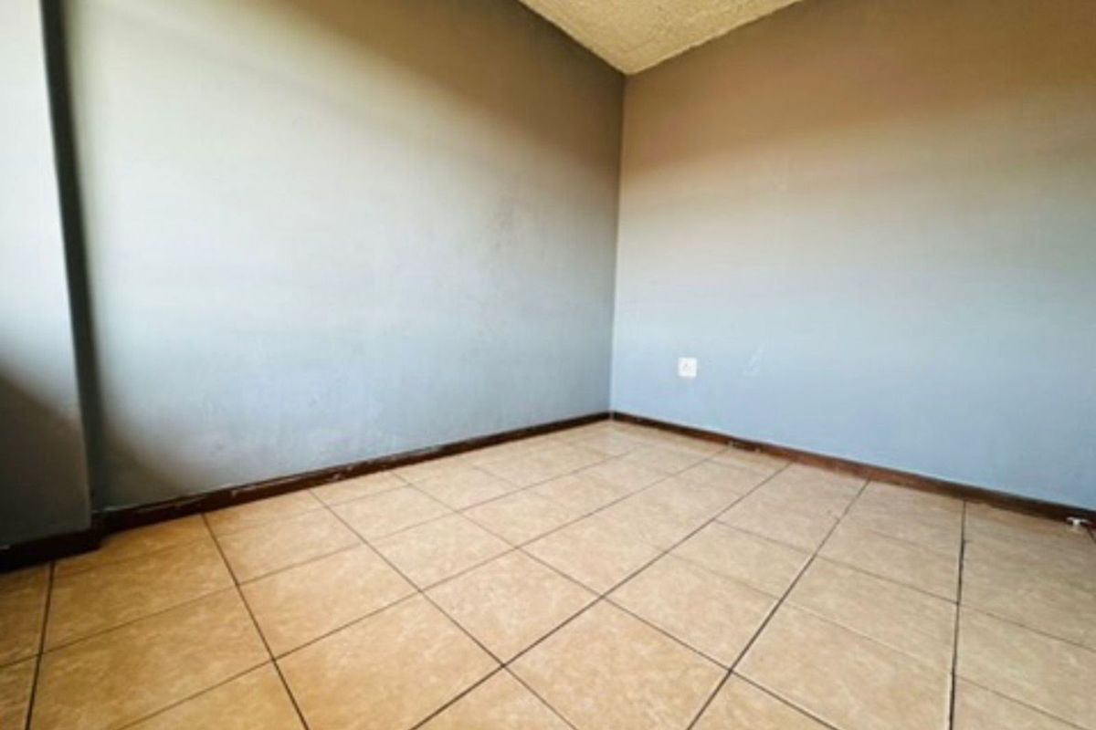An empty bedroom featuring tiled flooring and neutral painted walls, providing a blank canvas for personalization.