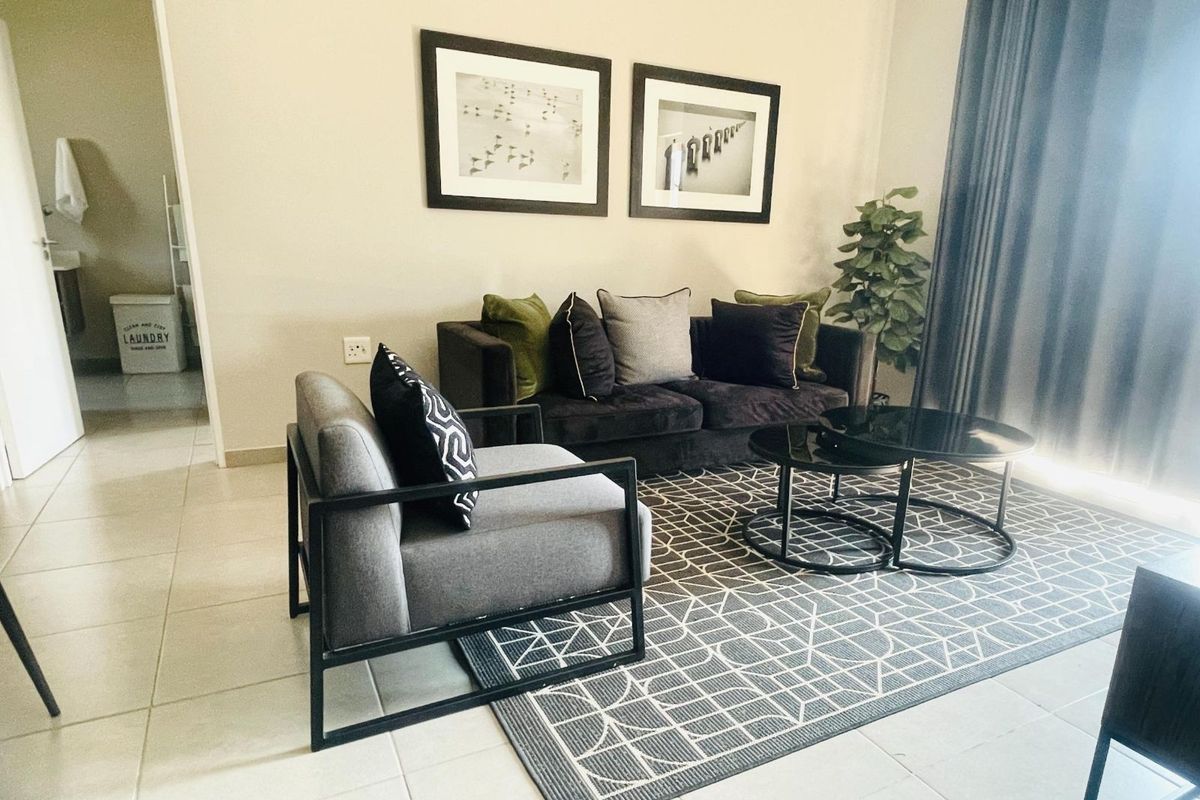 A comfortable living room featuring tiled flooring and a doorway leading to a laundry area.