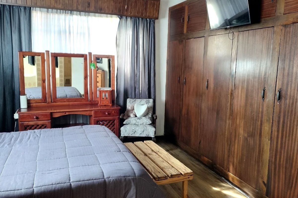 A bedroom featuring extensive floor-to-ceiling built-in wooden wardrobes and wood-paneled ceiling detailing, providing ample storage space.