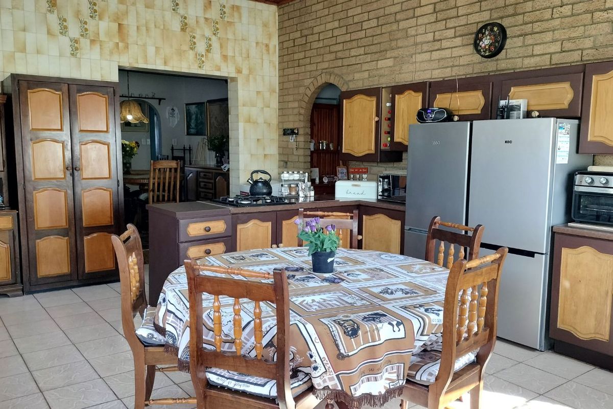 A dated kitchen featuring traditional wooden cabinetry, brick wall accents, and tiled flooring, offering a functional layout with potential for modern renovation.