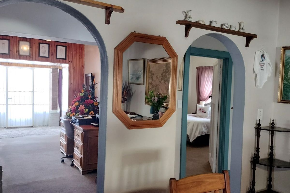 Interior view showing arched doorways connecting living spaces, featuring wood-paneled walls in the adjacent room and traditional architectural detailing.