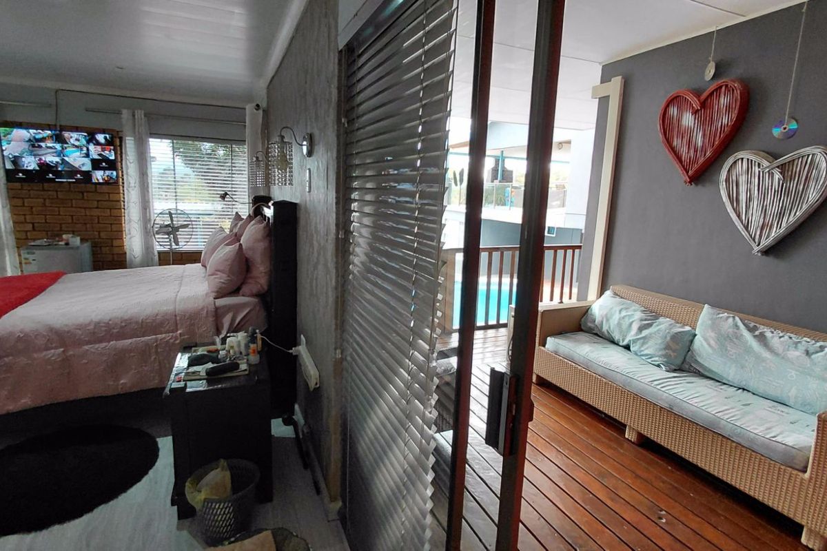 A bedroom featuring an adjoining covered patio with timber decking, providing direct access to an outdoor pool area.