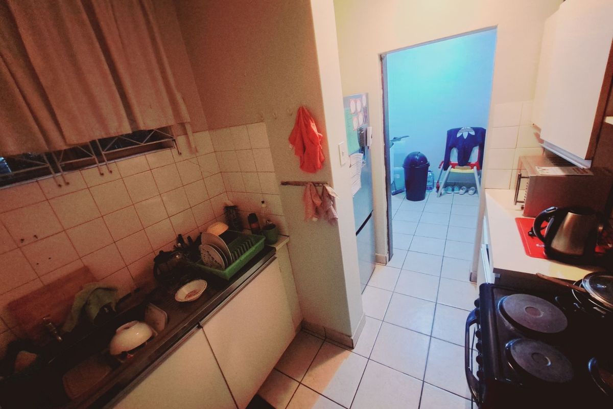 A functional kitchen featuring tiled splashbacks, built-in cabinetry, and a stove, with an adjacent utility area visible through the doorway.