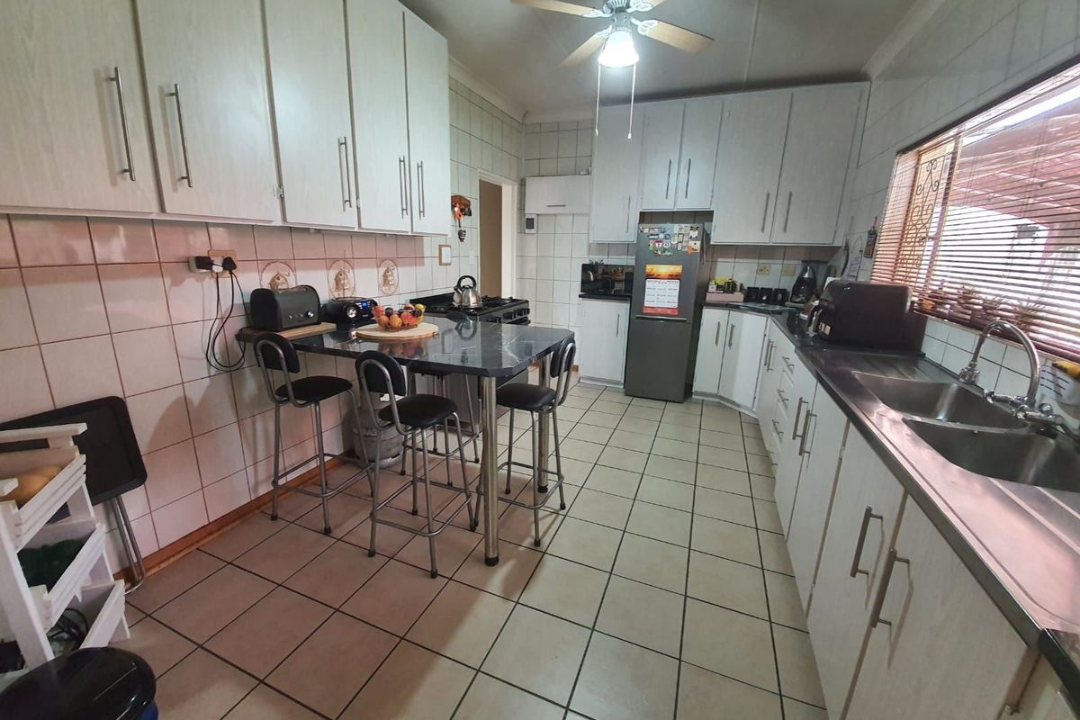 Functional kitchen featuring white cabinetry, tiled walls, tiled flooring, a breakfast bar, and a double stainless steel sink.