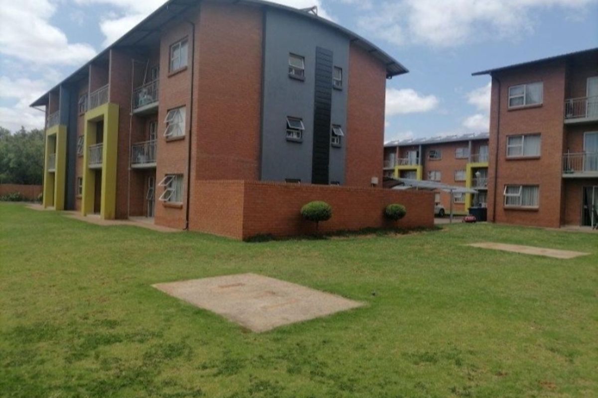 Exterior view of a multi-story brick apartment complex featuring landscaped grounds and private balconies.