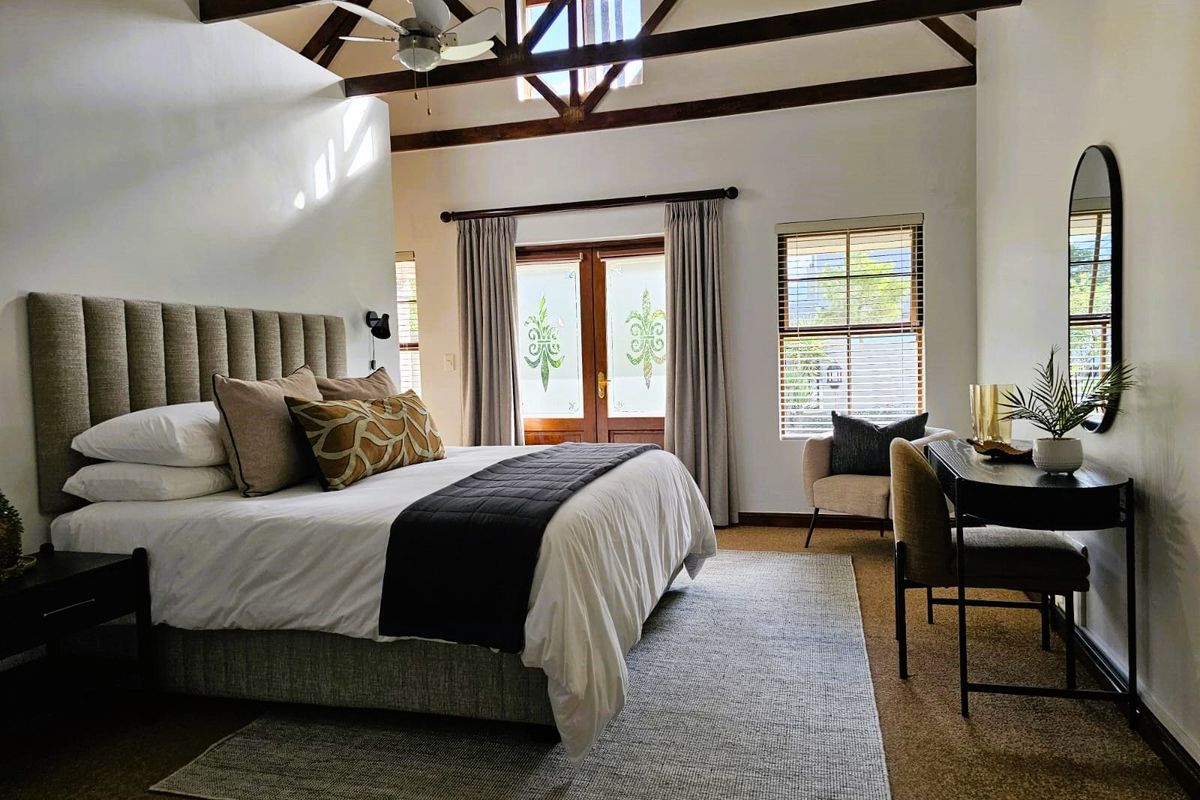 Spacious bedroom featuring high vaulted ceilings with exposed timber trusses, a ceiling fan, and double doors leading to the exterior.
