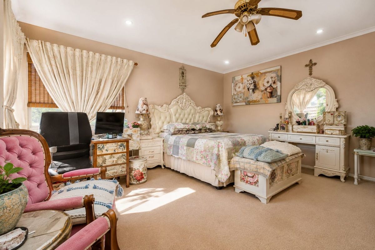 A spacious bedroom featuring neutral wall tones, carpeted flooring, and a ceiling fan, offering a comfortable and functional living space.