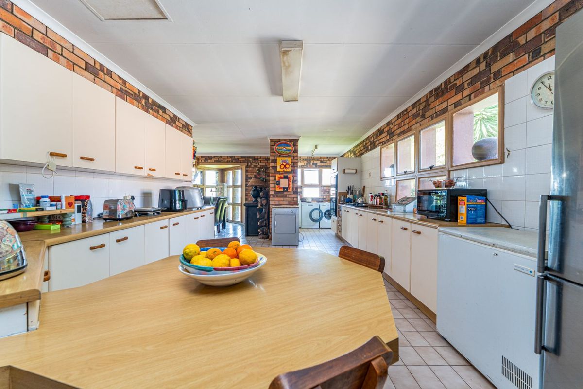 Spacious kitchen featuring extensive cabinetry, brick wall accents, and a central breakfast nook, offering a functional layout with direct access to the laundry area.