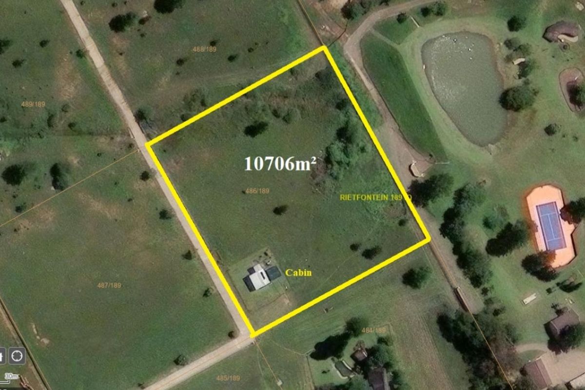 Aerial view of a 10,706 square meter farm plot featuring a cabin structure and surrounding open land.
