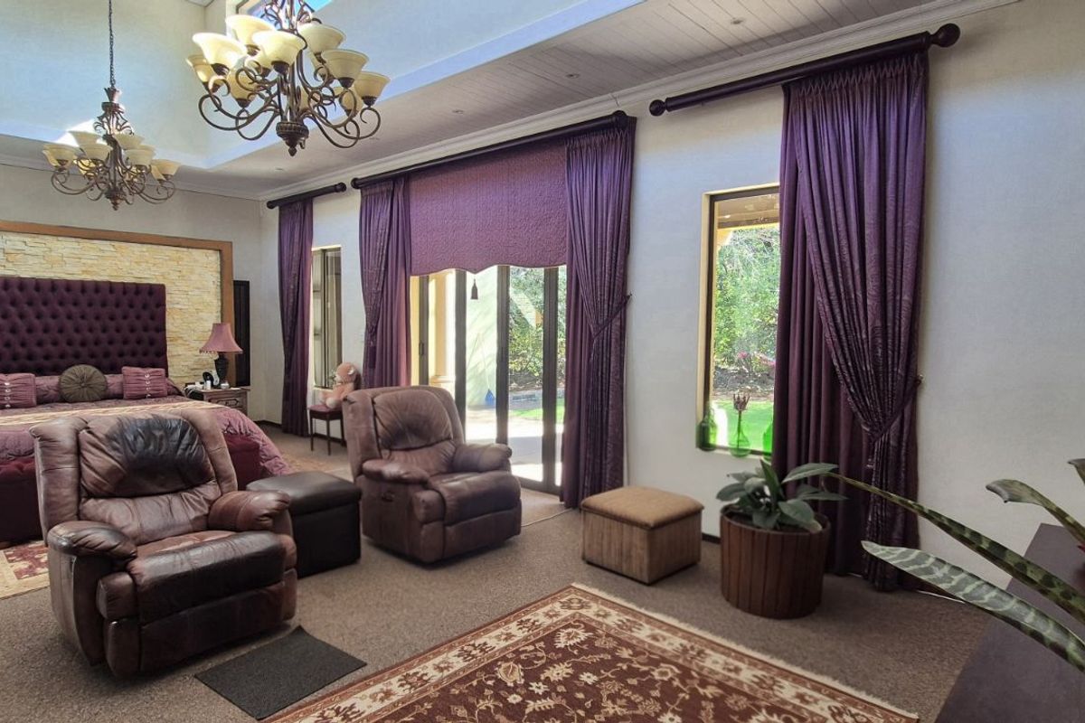 Spacious bedroom featuring high vaulted ceilings, stone feature wall, and large glass sliding doors providing direct access to the garden area.