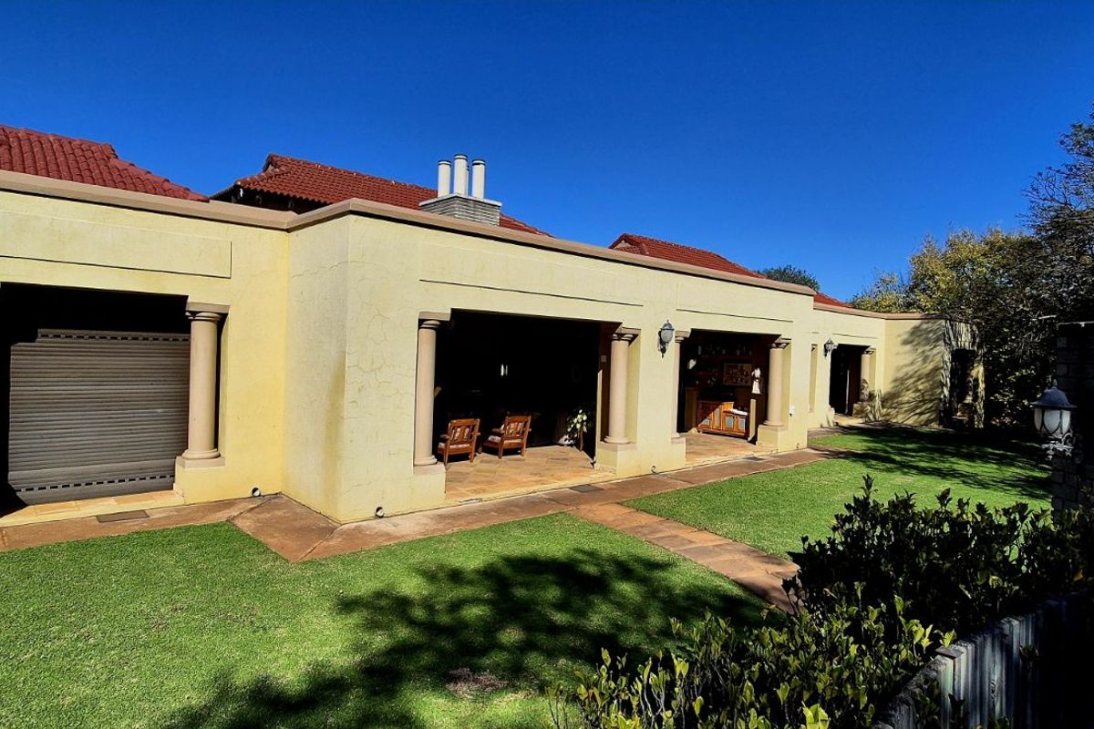 Spacious rear patio area featuring classic columns, tiled flooring, and direct access to the landscaped garden and lawn.