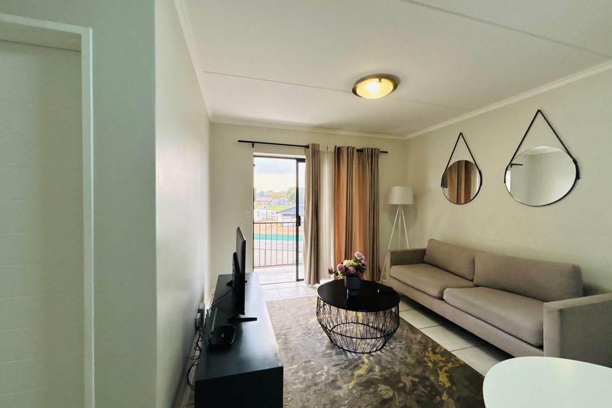 A bright living room featuring tiled flooring and a sliding glass door providing access to a private balcony.