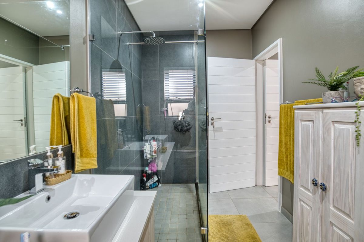 Modern bathroom featuring a walk-in glass shower with dark grey tiling, a contemporary vanity basin, and neutral wall finishes.