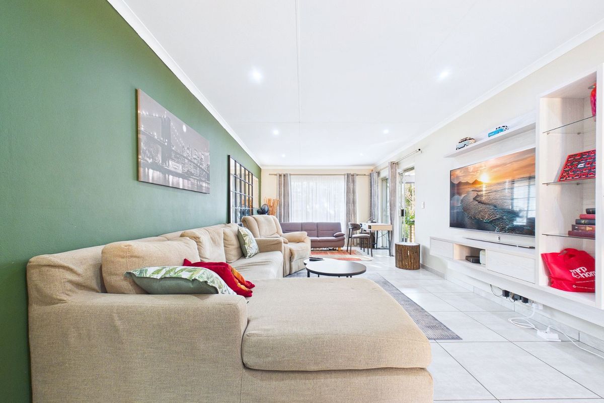 Spacious living room featuring tiled flooring, recessed ceiling lighting, and a built-in media unit with shelving.