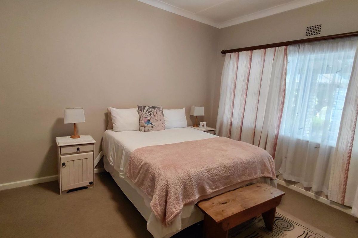 A well-maintained bedroom featuring neutral wall tones, built-in cabinetry, and large windows with curtain treatments, providing a comfortable and functional living space.