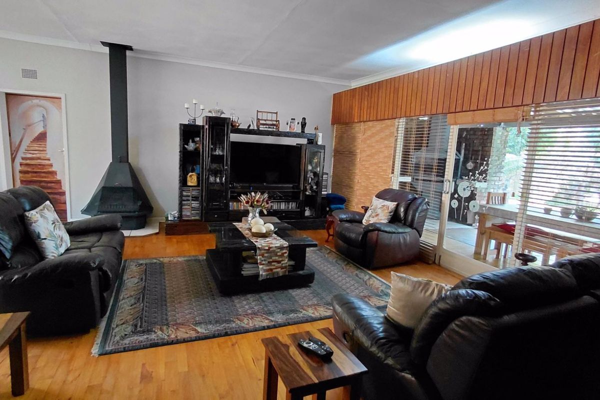 Spacious living room featuring a freestanding fireplace, timber flooring, and large sliding glass doors providing access to the outdoor patio area.