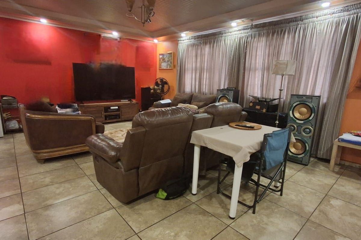 Spacious living room featuring tiled flooring, recessed lighting, and a prominent accent wall, providing a functional and comfortable family entertainment area.