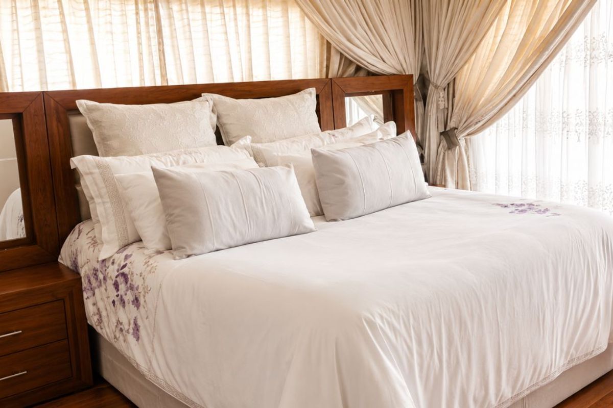 A well-maintained bedroom featuring warm timber flooring and integrated wooden headboard cabinetry with built-in mirrors.