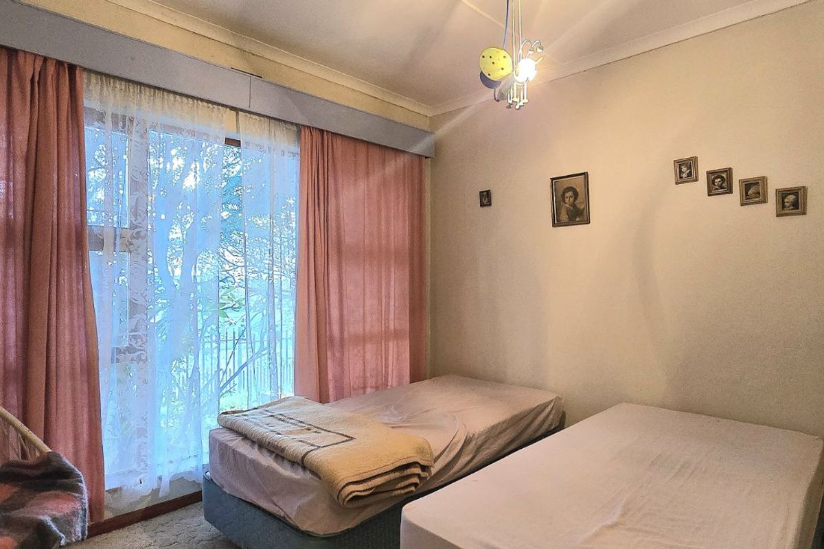 A bedroom featuring large windows with curtains, providing natural light and access to the exterior.