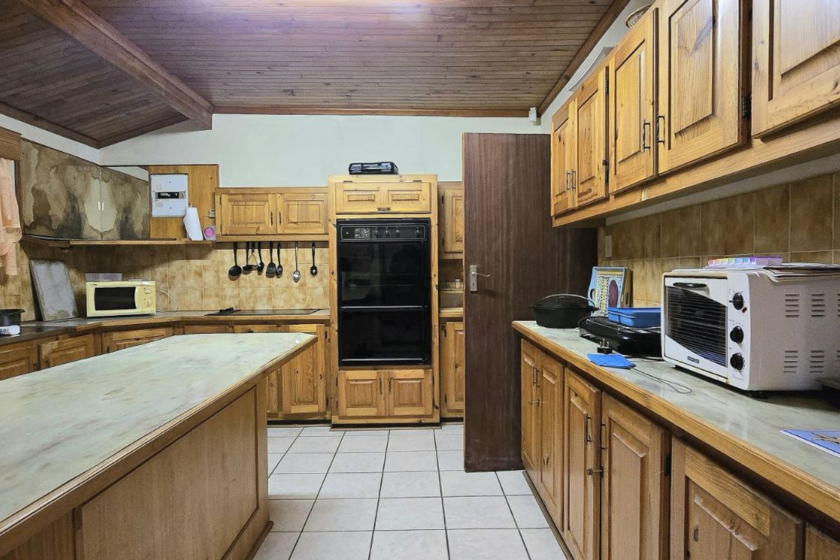 Spacious kitchen featuring extensive wooden cabinetry, a central island, built-in oven, and tiled flooring, offering significant potential for a modern renovation.