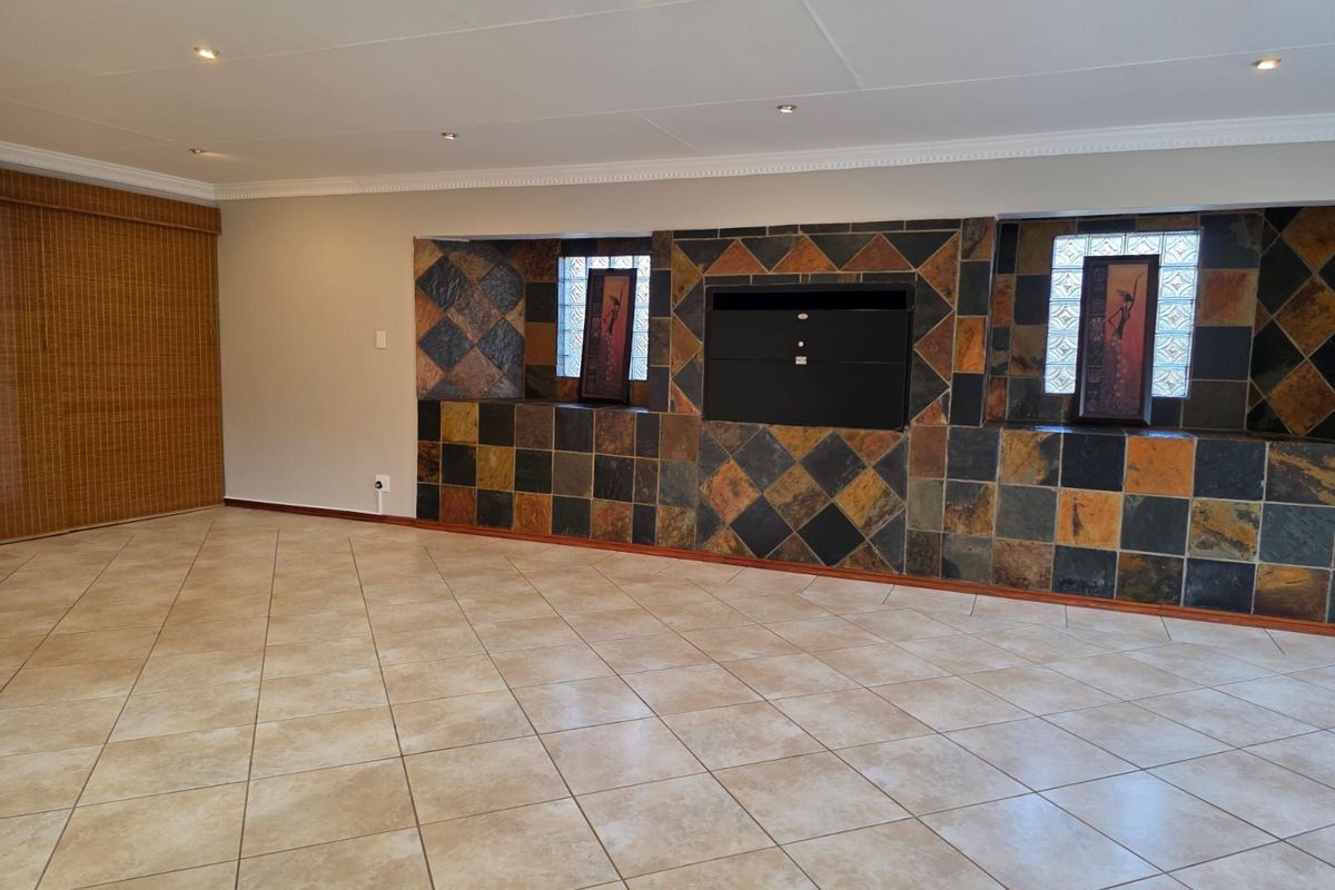 Spacious living area featuring a built-in fireplace with decorative slate tile surround, glass block windows, and neutral ceramic floor tiling.
