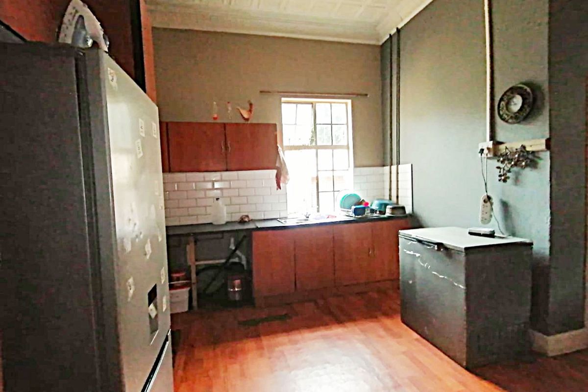 A dated kitchen featuring wooden cabinetry, a tiled backsplash, and exposed electrical conduit, offering potential for modernization and renovation.
