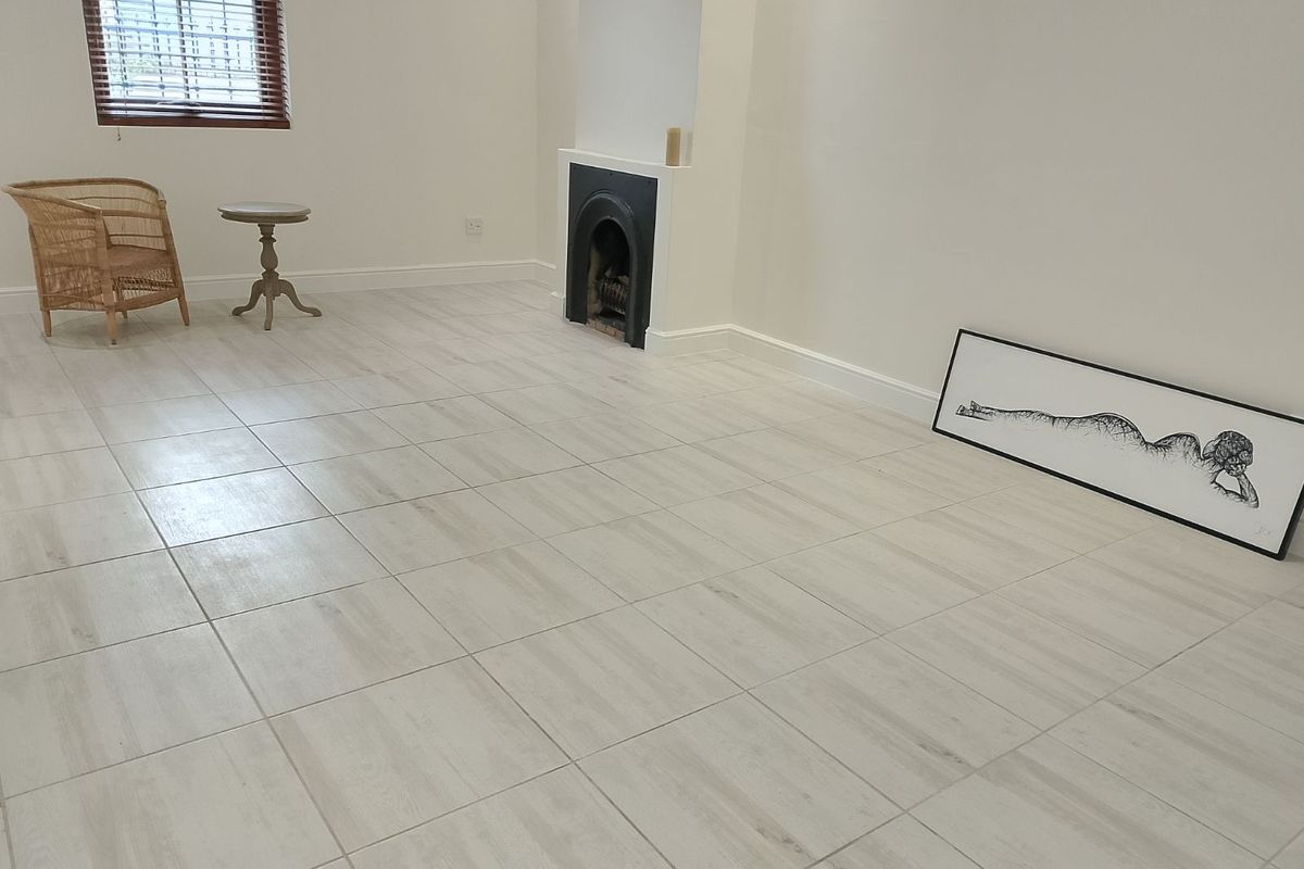 A bright, spacious living room featuring light-toned floor tiles and a classic built-in fireplace, offering a clean and neutral canvas for interior design.